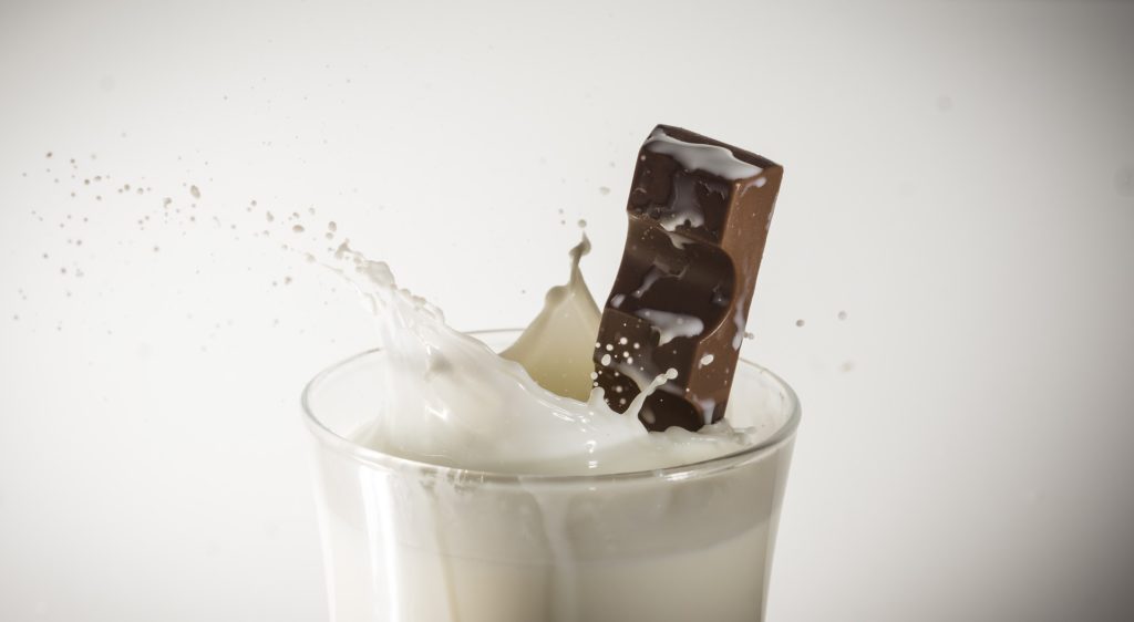 a chocolate bar splashing into a glass of milk