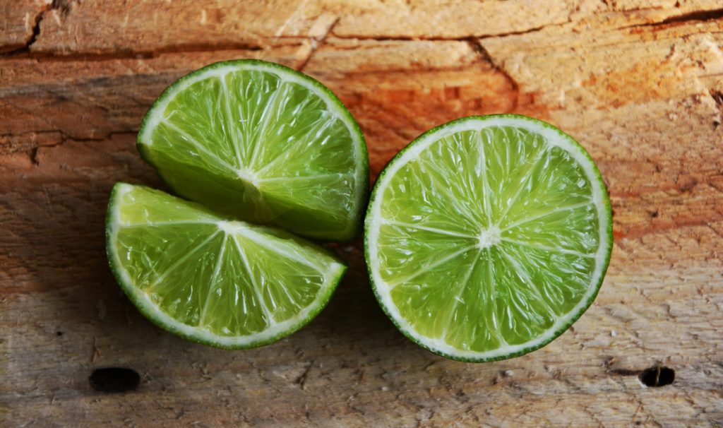 a lime cut open on a cutting board, one half cut in half